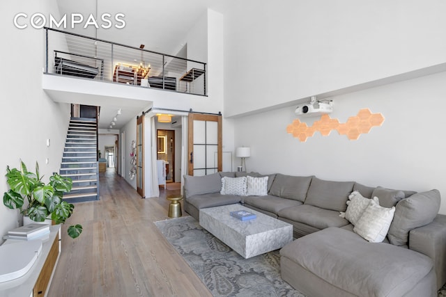 90 Furman St Unit N609, New York City, NY 11201 - living area featuring a barn door, a towering ceiling, stairs, and wood finished floors