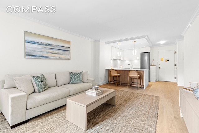living room with ornamental molding, light wood-style flooring, and baseboards