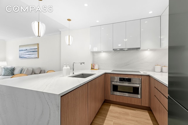 kitchen with stainless steel appliances, a sink, modern cabinets, a peninsula, and open floor plan