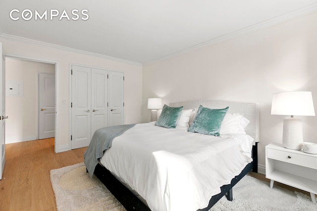 bedroom featuring light wood finished floors, ornamental molding, a closet, and baseboards