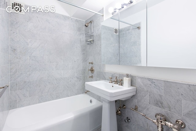 bathroom featuring shower / washtub combination and tile walls