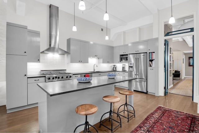 kitchen featuring dark countertops, light wood-style floors, wall chimney exhaust hood, a sink, and appliances with stainless steel finishes