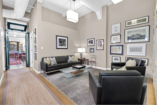 living area with baseboards, a high ceiling, and wood finished floors