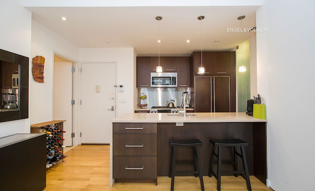 342 E 110th St Unit 3D, New York City, NY 10029 - kitchen featuring paneled fridge, stainless steel microwave, dark brown cabinets, modern cabinets, and light countertops