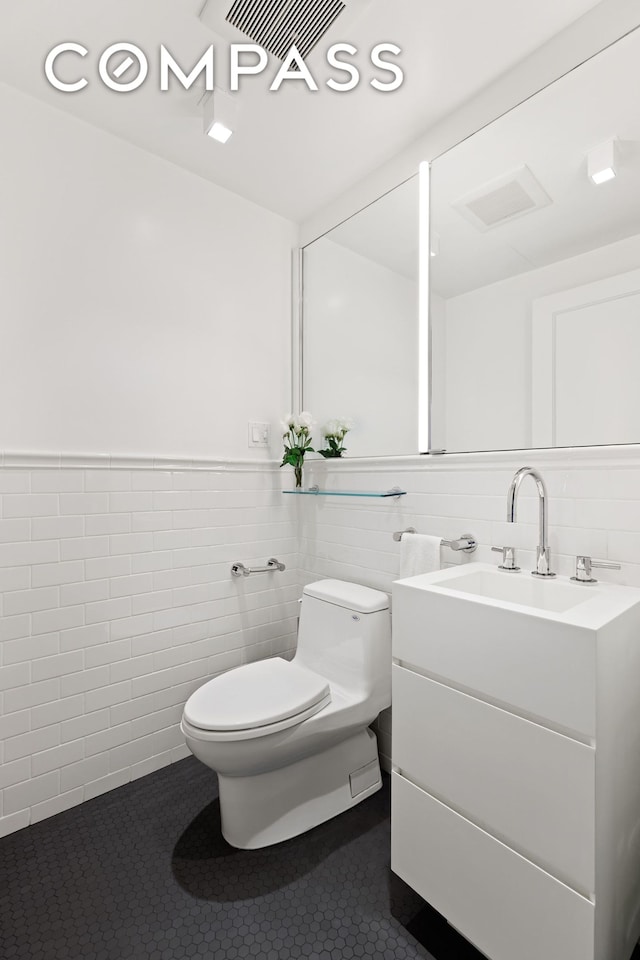 863 Park Ave Unit 8W, New York City, NY 10075 - half bath featuring tile patterned flooring, vanity, tile walls, toilet, and wainscoting