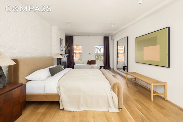 bedroom featuring a brick fireplace and light wood-type flooring