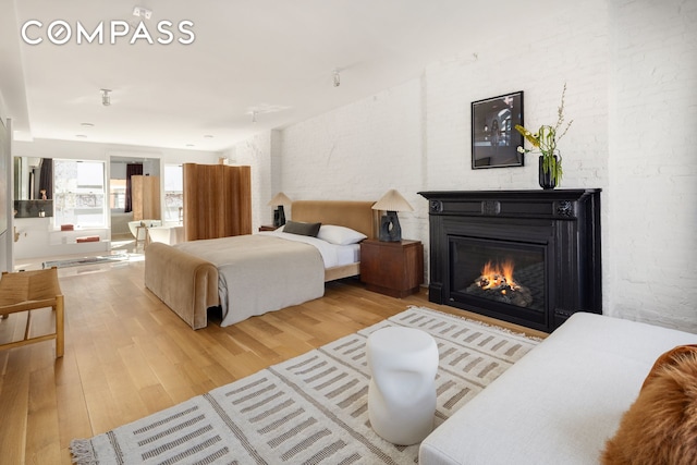 bedroom featuring a glass covered fireplace and wood finished floors