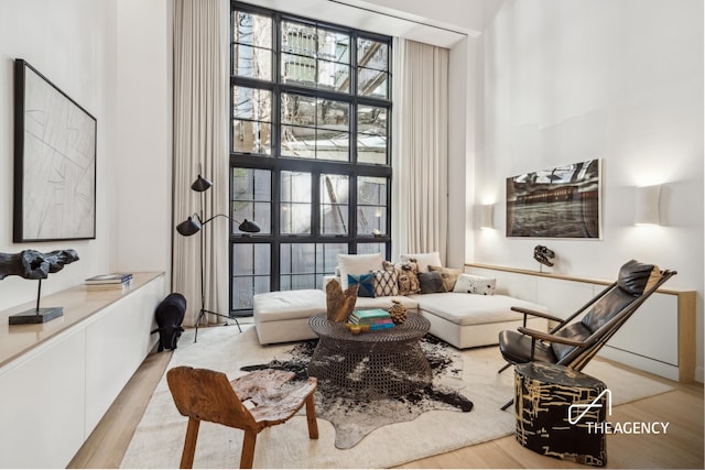 sitting room featuring a towering ceiling and light wood-style flooring