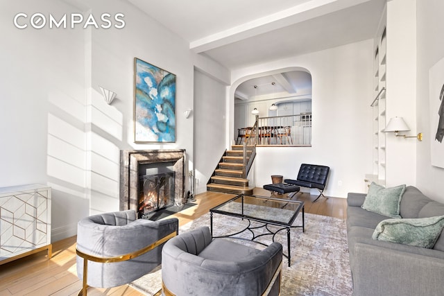 434 E 52nd St Unit 10E, New York City, NY 10022 - living room with arched walkways, wood finished floors, a glass covered fireplace, baseboards, and beamed ceiling