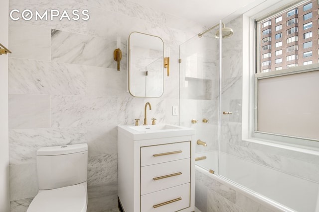 434 E 52nd St Unit 10E, New York City, NY 10022 - bathroom featuring tile walls, tiled shower / bath combo, vanity, and toilet