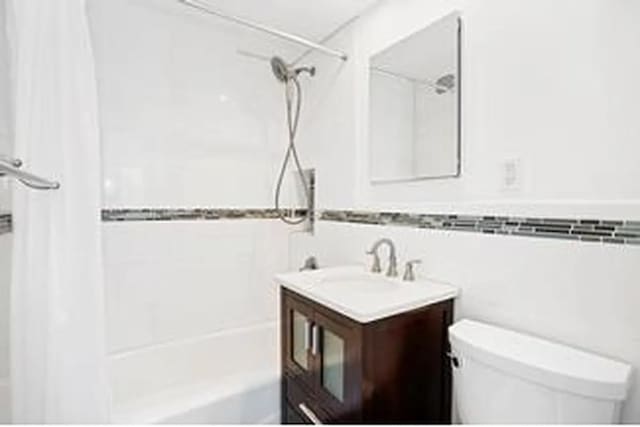 bathroom with toilet, shower / washtub combination, vanity, and tile walls