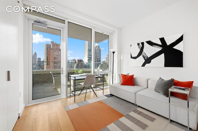 living room featuring a view of skyline, wood finished floors, expansive windows, and a desk
