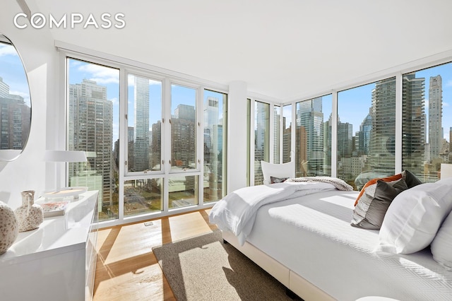 301 E 61st St Unit 16A, New York City, NY 10065 - bedroom with a view of skyline, light wood-type flooring, access to exterior, and expansive windows
