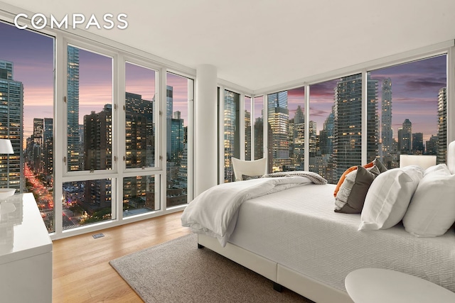 301 E 61st St Unit 16A, New York City, NY 10065 - bedroom featuring a skyline view, wood finished floors, and a wall of windows