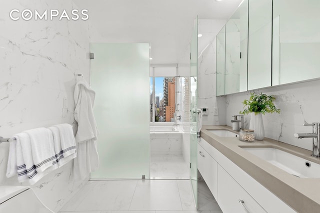 bathroom with a garden tub, double vanity, marble finish floors, and a city view