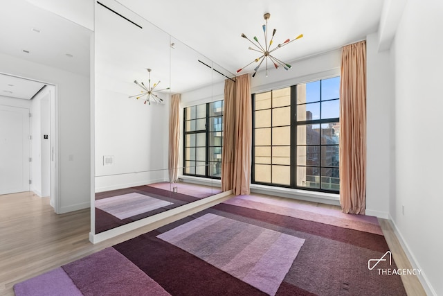 200 11th Ave Unit 7S, New York City, NY 10011 - unfurnished dining area with a chandelier, baseboards, and wood finished floors