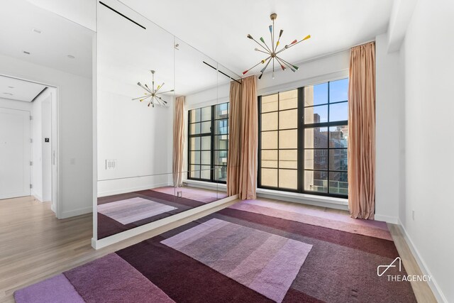 200 11th Ave Unit 7S, New York City, NY 10011 - unfurnished dining area with a chandelier, baseboards, and wood finished floors