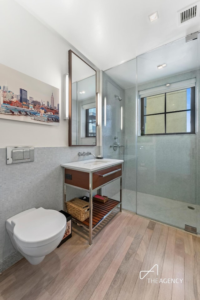 200 11th Ave Unit 7S, New York City, NY 10011 - full bathroom with tile walls, wood finished floors, tiled shower, vanity, and plenty of natural light