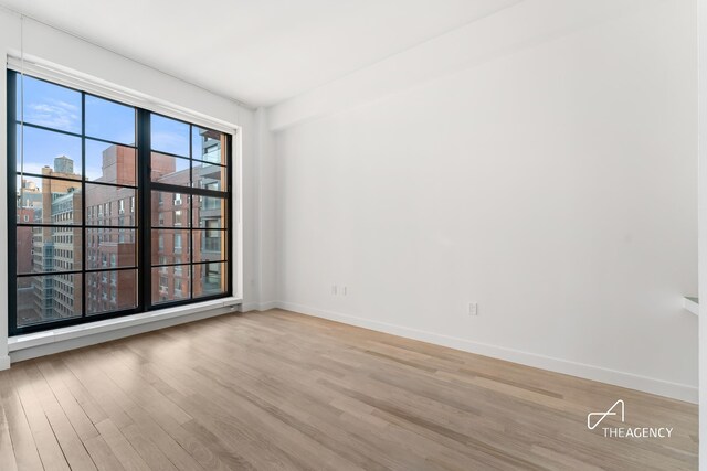 200 11th Ave Unit 7S, New York City, NY 10011 - empty room featuring wood finished floors, baseboards, and a view of city