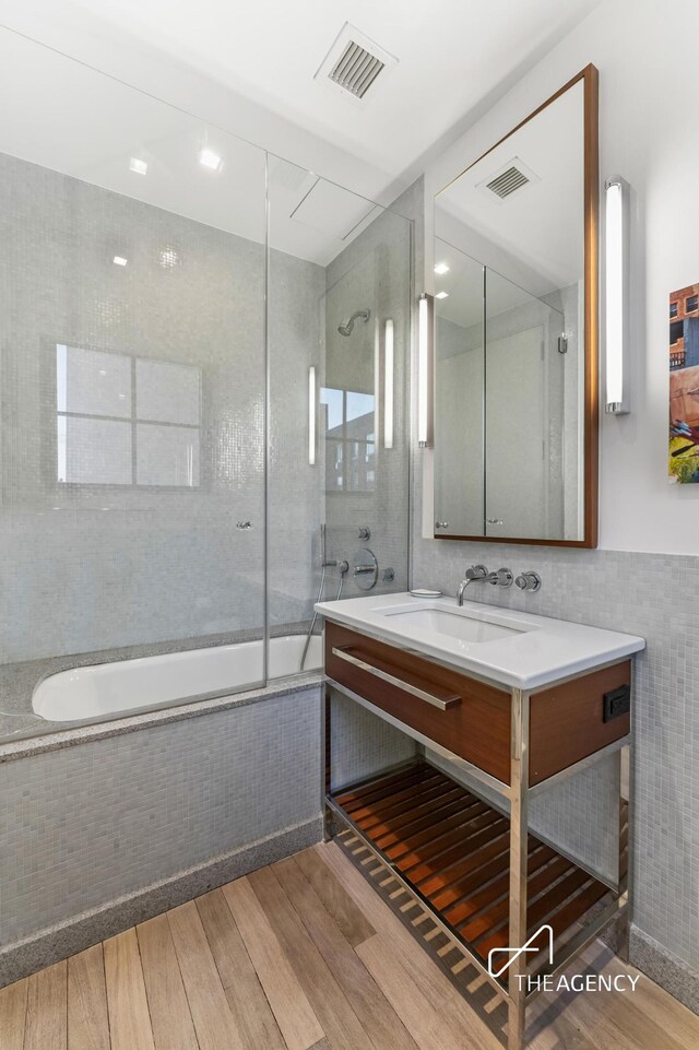 200 11th Ave Unit 7S, New York City, NY 10011 - full bathroom with wood finished floors, vanity, tiled shower / bath combo, and tile walls