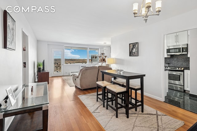 dining room with an inviting chandelier, wood finished floors, and baseboard heating