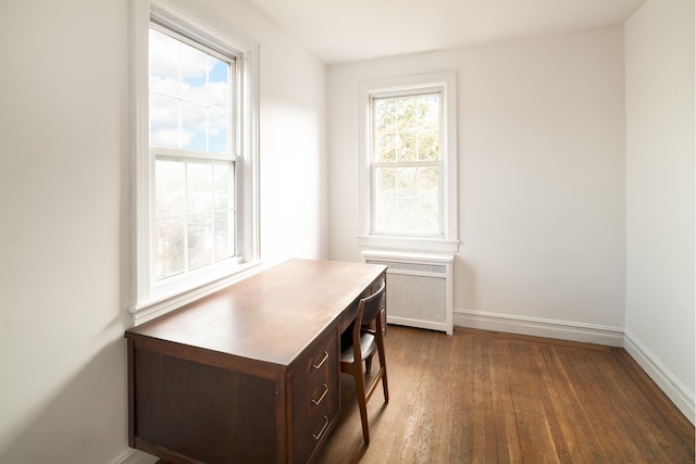 office space featuring radiator heating unit, baseboards, and dark wood-style floors