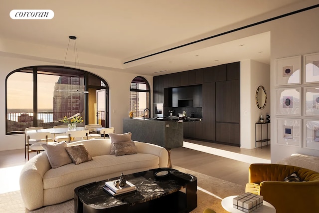 living area with light wood finished floors, arched walkways, visible vents, and a wealth of natural light