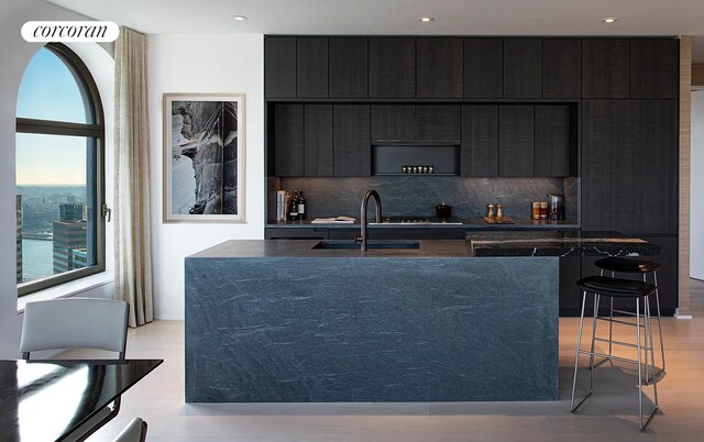 130 William St Unit 43C, New York City, NY 10038 - kitchen with dark cabinets, tasteful backsplash, an island with sink, modern cabinets, and recessed lighting