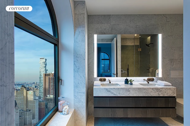 130 William St Unit 43C, New York City, NY 10038 - bathroom with double vanity, toilet, a stall shower, and a view of city