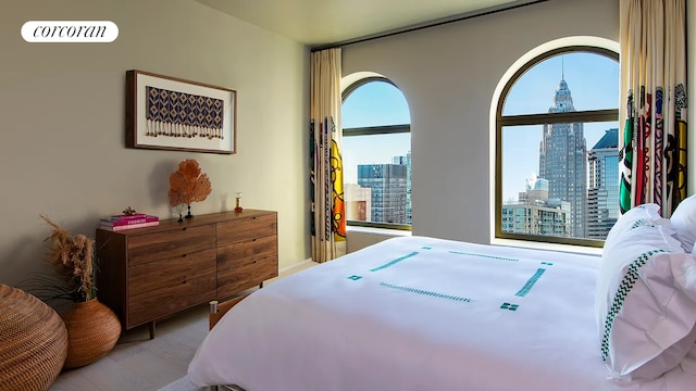 bedroom with a view of city and wood finished floors