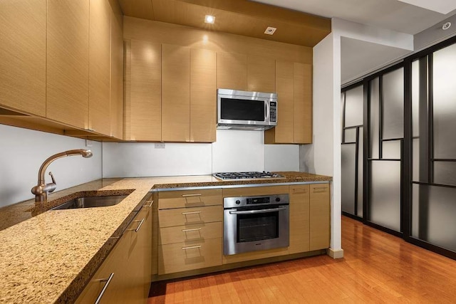 1600 Broadway Unit 18C, New York City, NY 10019 - kitchen with appliances with stainless steel finishes, a sink, light wood-type flooring, light stone counters, and modern cabinets