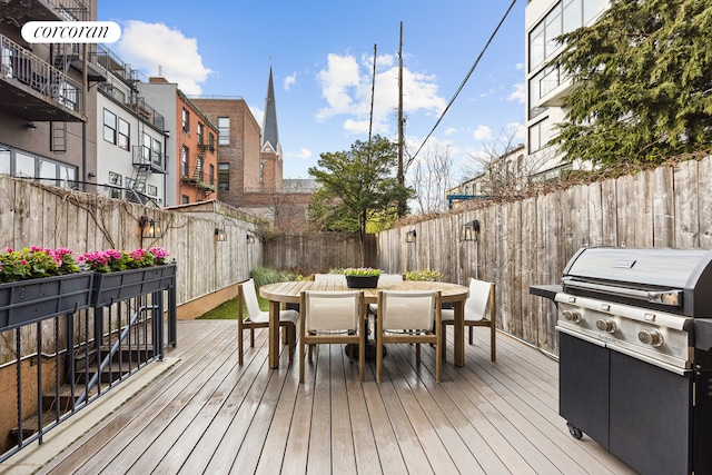 deck with area for grilling, outdoor dining space, a fenced backyard, and a residential view