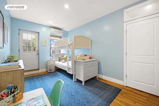 bedroom featuring a wall mounted AC, wood finished floors, baseboards, and recessed lighting