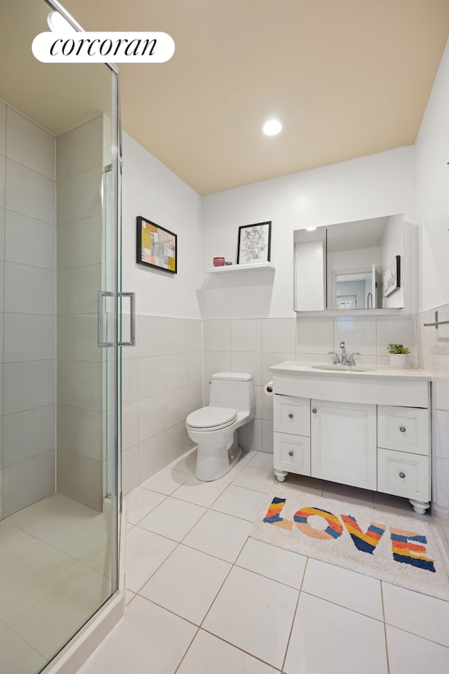 bathroom with tile walls, a stall shower, tile patterned floors, toilet, and vanity