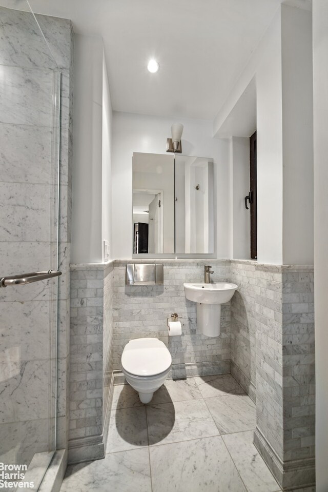 345 E 57th St Unit 8Ab, New York City, NY 10022 - full bath with tile walls, toilet, marble finish floors, a stall shower, and wainscoting