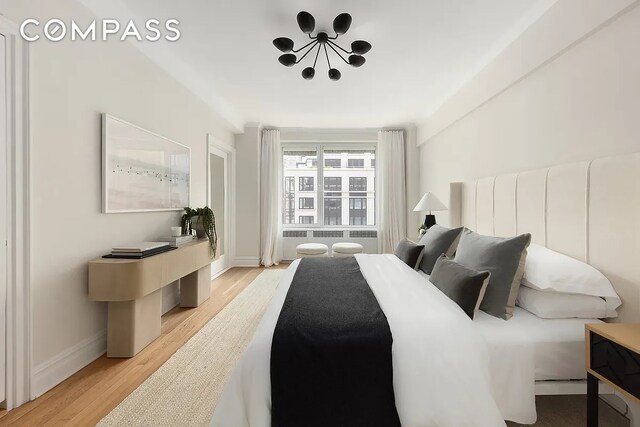 bedroom with baseboards, light wood-style flooring, a chandelier, and radiator