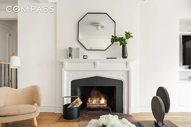 interior space with a fireplace with flush hearth and wood finished floors