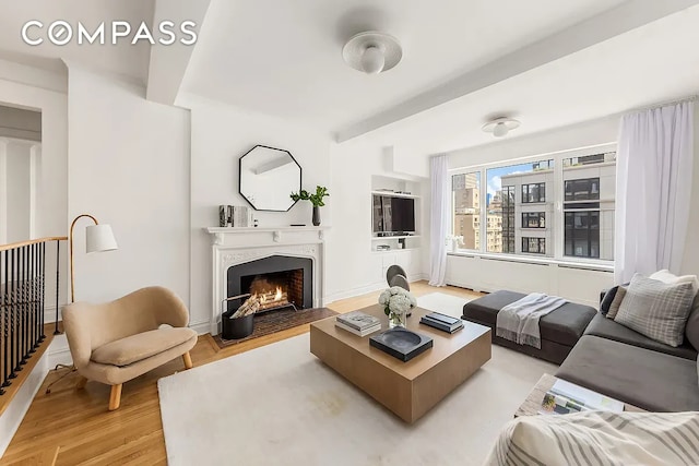 living area featuring baseboards, a fireplace with flush hearth, and light wood-style floors