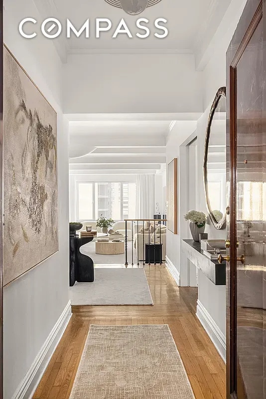 corridor featuring wood-type flooring, baseboards, and crown molding