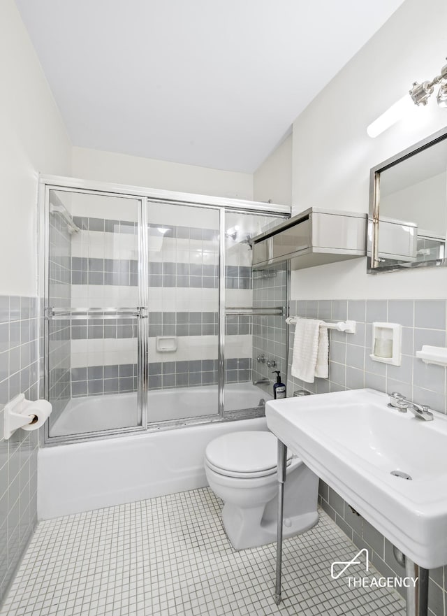 230 E 79th St Unit 4D, New York City, NY 10075 - full bathroom featuring tile walls, toilet, shower / bath combination with glass door, tile patterned floors, and wainscoting