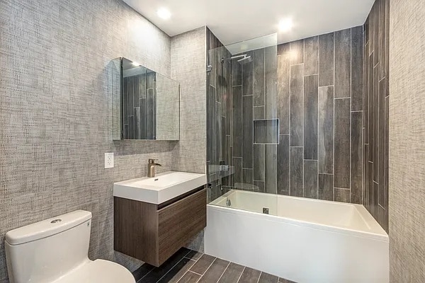 bathroom with toilet, tile walls, vanity, and bathtub / shower combination