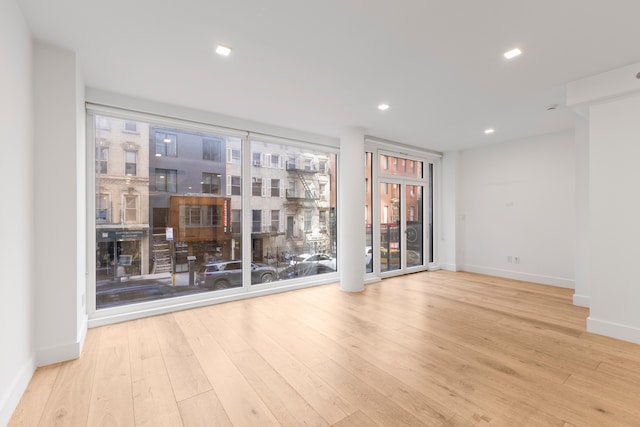 unfurnished room featuring wood finished floors, baseboards, and recessed lighting