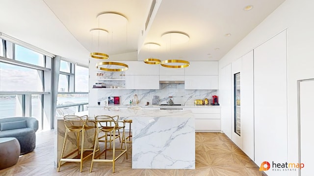 kitchen featuring modern cabinets, tasteful backsplash, a kitchen island, and white cabinetry