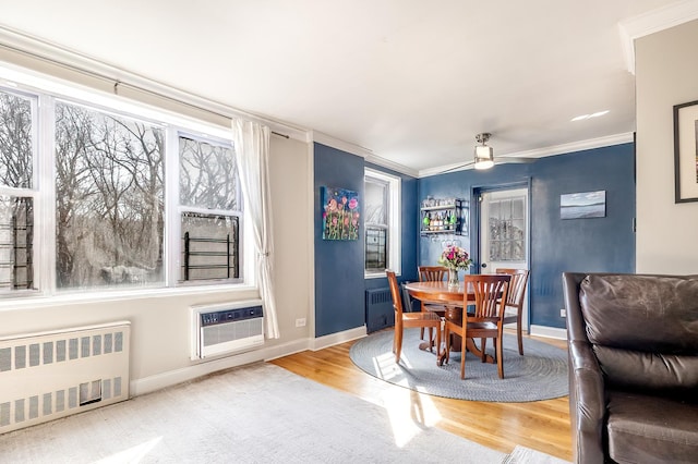 dining area featuring ornamental molding, radiator, wood finished floors, baseboards, and a wall unit AC