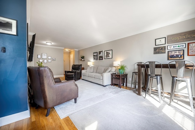 living area featuring baseboards, ornamental molding, and wood finished floors