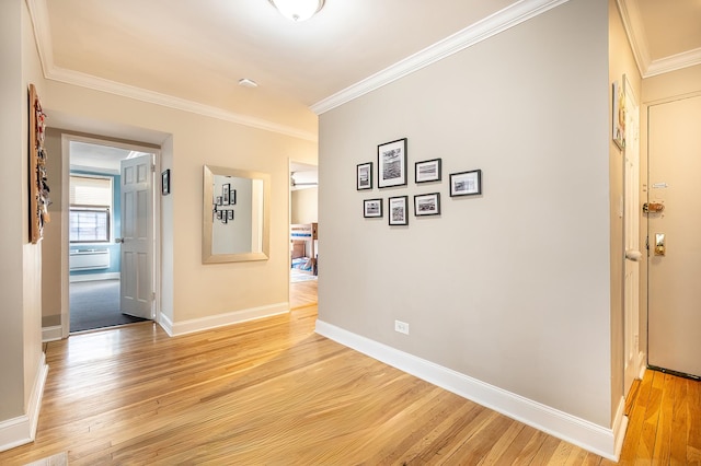hallway featuring crown molding, baseboards, and light wood finished floors