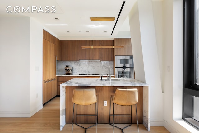 kitchen with modern cabinets, a sink, stainless steel double oven, and brown cabinets