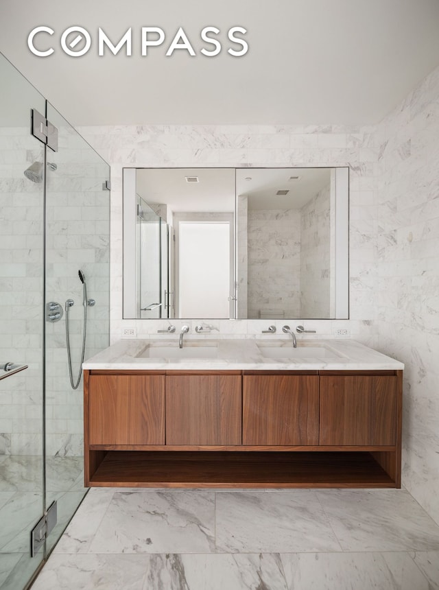 full bathroom featuring a stall shower, double vanity, and marble finish flooring