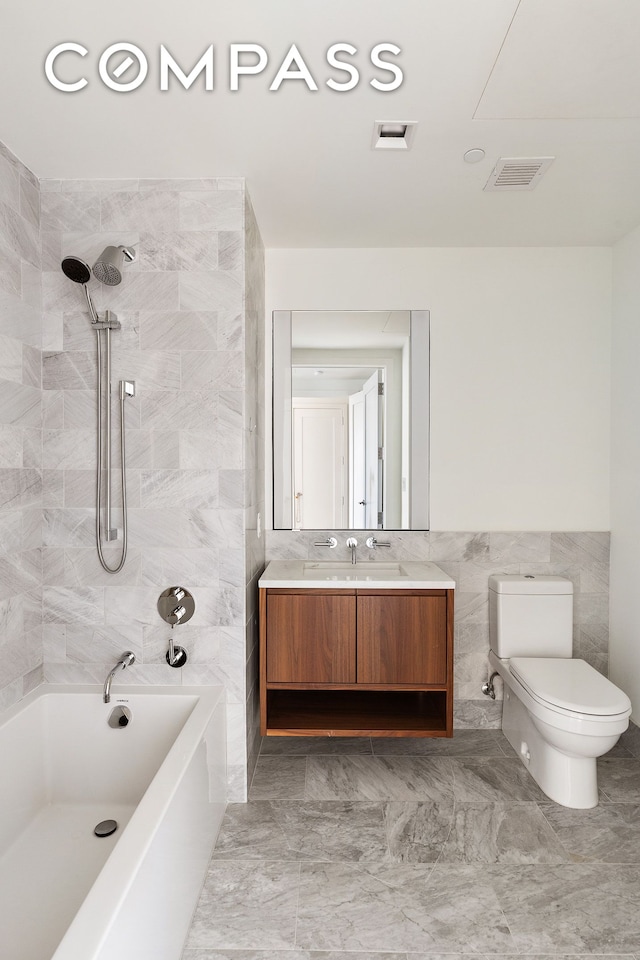 full bathroom featuring toilet, tile walls, vanity, and shower / washtub combination
