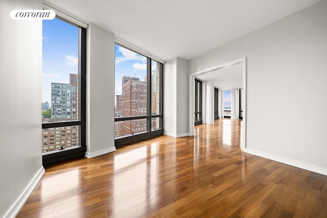 101 Warren St Unit 1720, New York City, NY 10007 - spare room featuring a view of city, floor to ceiling windows, and wood finished floors